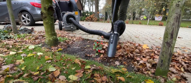 a person using a machine to clear leafs that have fallen