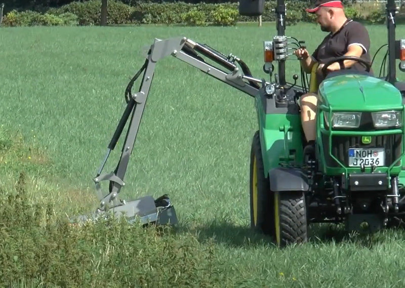 A man using a tractor with a Hydraulic Rear Mower attached
